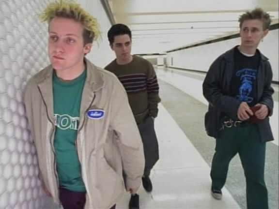 three young men walking down an escalator with one man looking at the camera