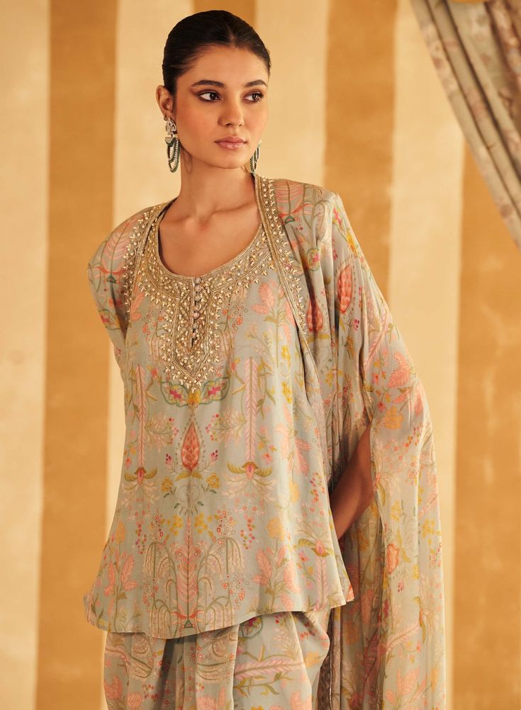 Step into serene elegance with the powder blue georgette printed embroidered sleeveless kurta and cape, paired with dhoti pants. The sleeveless kurta showcases a delicate print and intricate embroidery on airy georgette fabric, while the flowing cape adds a touch of sophisticated charm. The dhoti pants offer a modern yet traditional finish, creating a cohesive and stylish ensemble perfect for any festive or formal occasion. Eid Georgette Kurta With Cape Sleeves, Eid Kurta With Cape Sleeves In Georgette, Eid Festival Georgette Kurta With Cape Sleeves, Georgette Sets With Cape Sleeves For Festivals, Summer Georgette Sharara With Printed Motifs, Anarkali Palazzo Set With Cape Sleeves For Festivals, Summer Designer Kurta With Digital Print, Navratri Designer Palazzo Set With Cape Sleeves, Summer Designer Digital Print Kurta