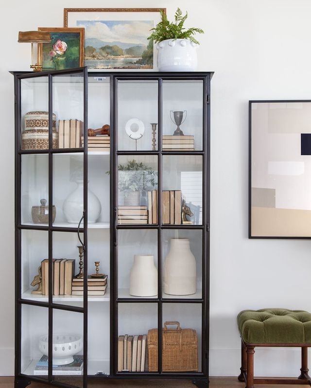 a black bookcase with glass doors and shelves filled with books on top of it