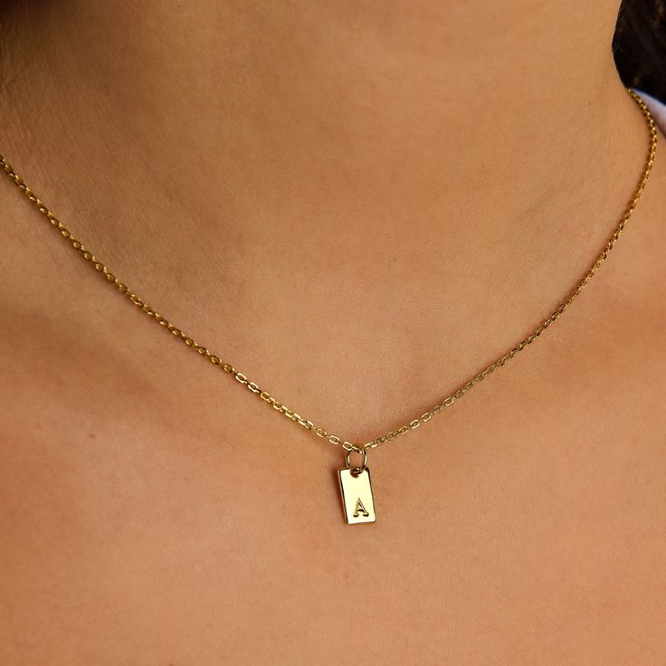 Double the charm and twice as personal, the Two Tiny Tag Initial Necklace is an exquisite celebration of identity and connection. Crafted in radiant gold, this necklace showcases two sleek rectangular pendants, each delicately engraved with a distinct initial. Add more initials that have meaning for you from our charm collection. However you customize the necklace, it will quickly become a favorite in your collection. Tag size: 10 mm x 5 mm Made of 14K gold-filled 18'' cable chain Hypoallergenic Rectangular Initials Jewelry For Personalized Gift, Rectangular Initials Jewelry For Anniversary, Rectangular Monogram Jewelry For Anniversary, Personalized Rectangular Initials Jewelry, Gold Rectangular Initial Necklace For Personalized Gift, Personalized Initial Square Pendant Necklace For Anniversary, Rectangular Initials Necklace For Personalized Gift, Personalized Square Pendant Initial Necklace For Anniversary, Elegant Personalized Necklace With Rectangular Links