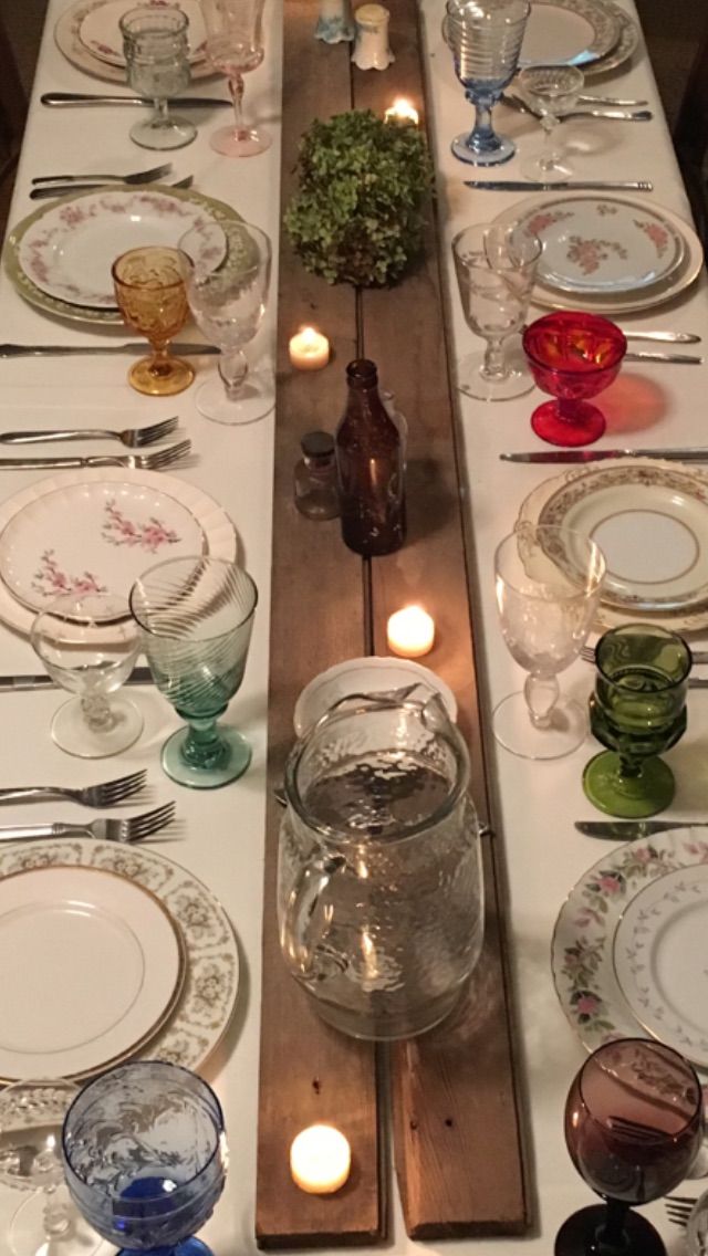 a long table with plates and candles on it is set up for a formal dinner