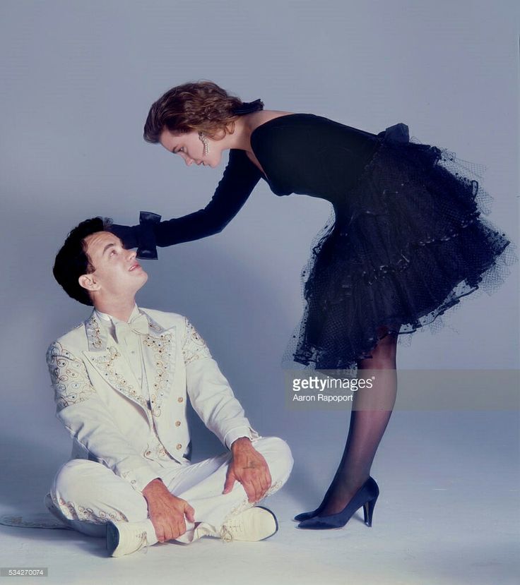 a man in a tuxedo is kneeling down next to a woman