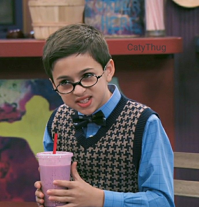 a young boy wearing glasses and holding a drink in front of him on the set of big bang