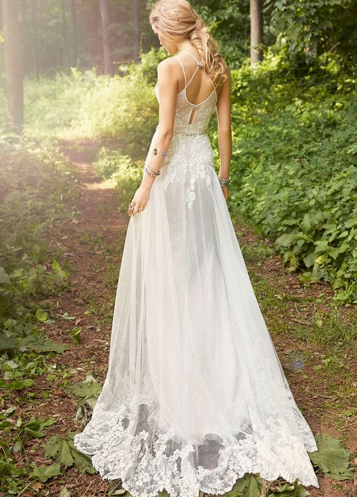 a woman standing in the woods wearing a wedding dress with an open back and lace detailing