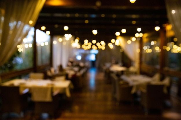 an empty restaurant with tables and chairs covered in white tablecloths, lights hanging from the ceiling