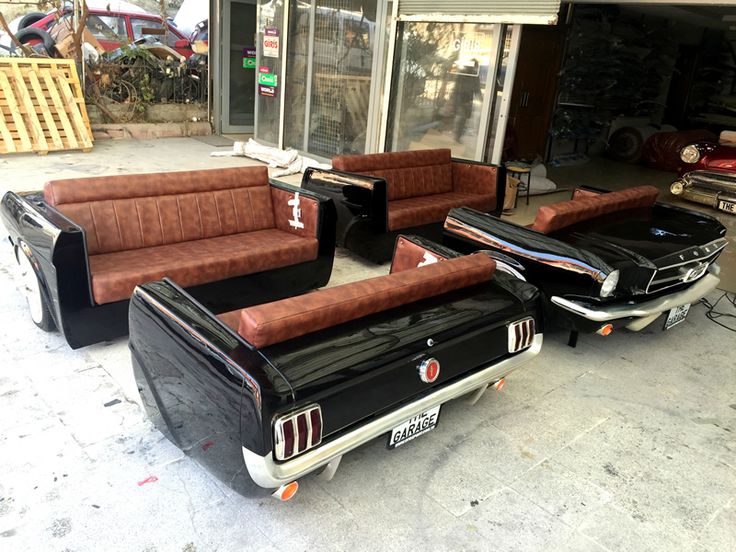 three couches sitting in front of a garage with other cars parked behind them on the street