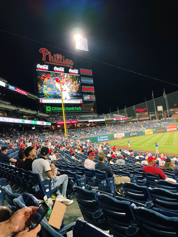 a baseball stadium filled with lots of people sitting on the bleachers at night