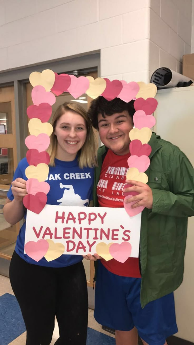 two people standing next to each other holding up a happy valentine's day sign