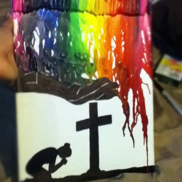 a person holding up a cross and painting with crayons