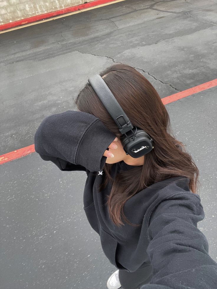 a woman with headphones on her ears is standing in the street and looking at something