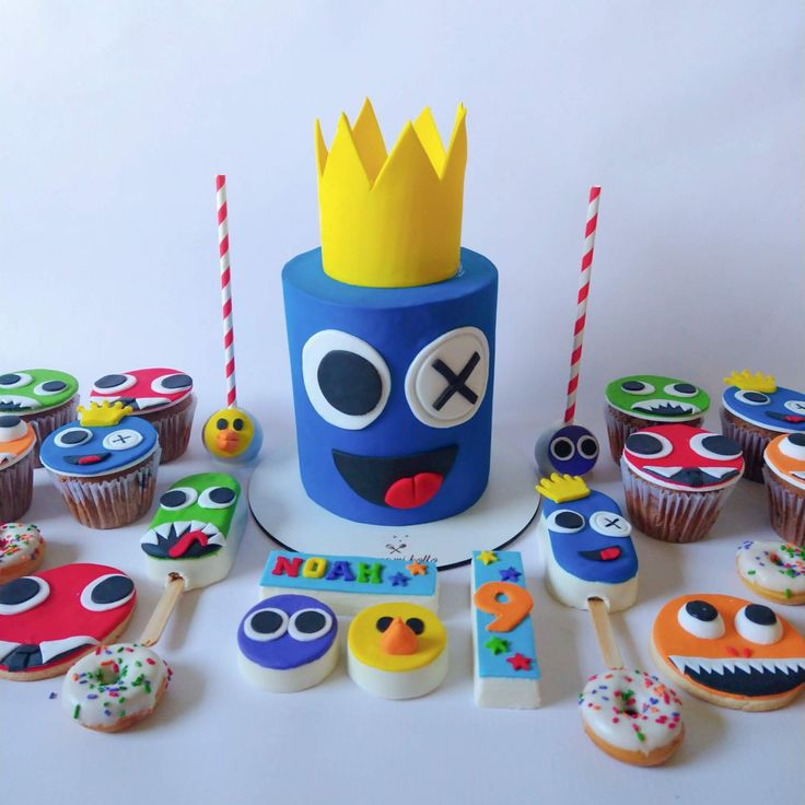 a birthday cake with cupcakes decorated as monsters and other decorations for a party