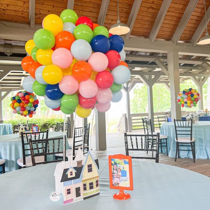 a bunch of balloons that are on top of a table in a room with tables and chairs