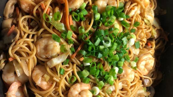 noodles with shrimp and scallops in a skillet, topped with green onions