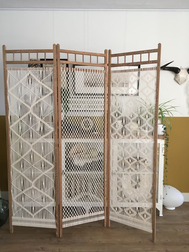 a room divider made out of wood and white mesh with an intricate design on the sides