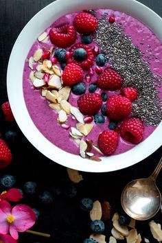 a bowl of smoothie with raspberries, almonds and blueberries in it