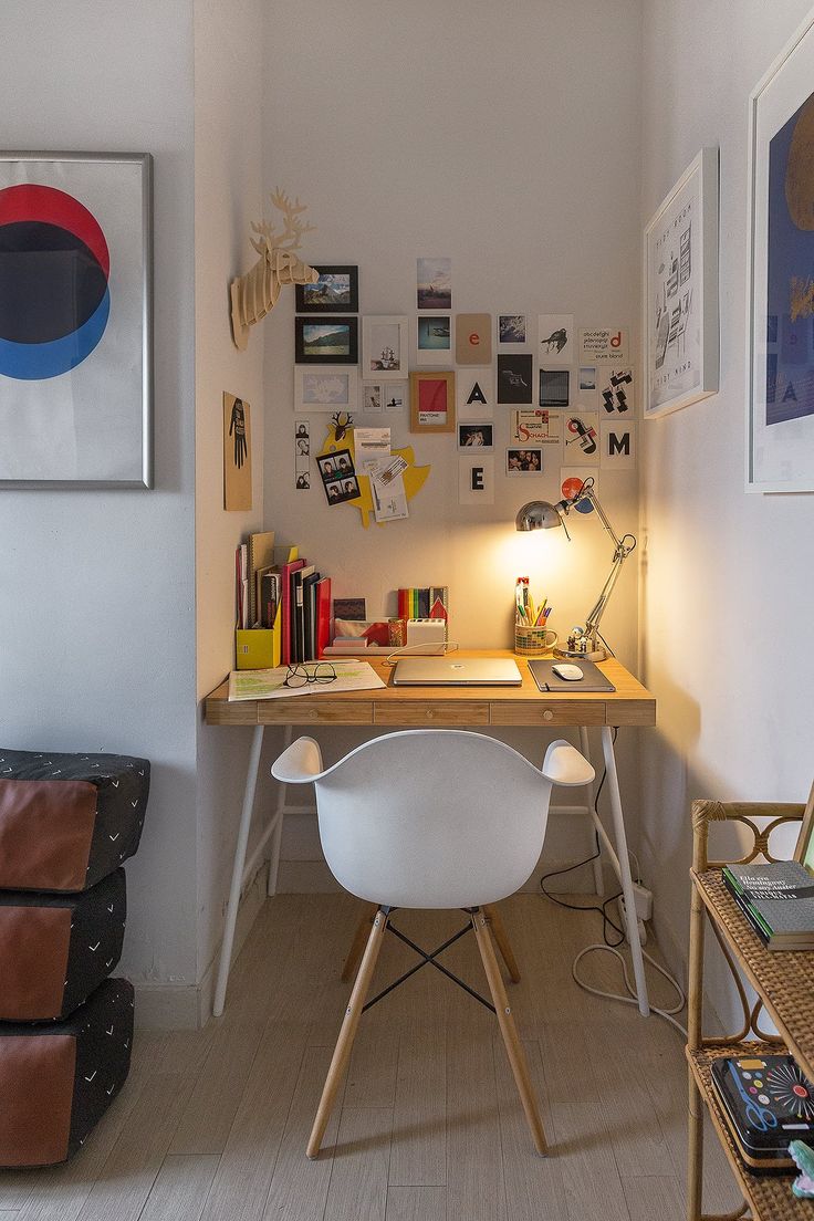 a room with a desk, chair and pictures on the wall above it is also a couch