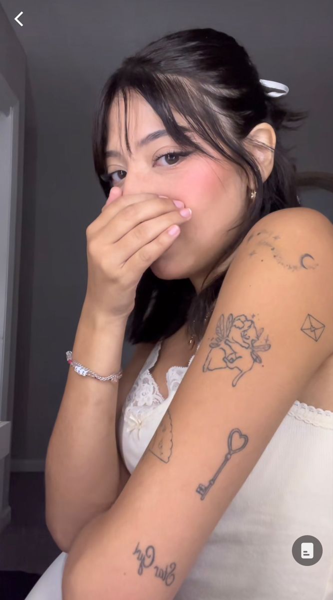 a woman with tattoos on her arm covering her mouth