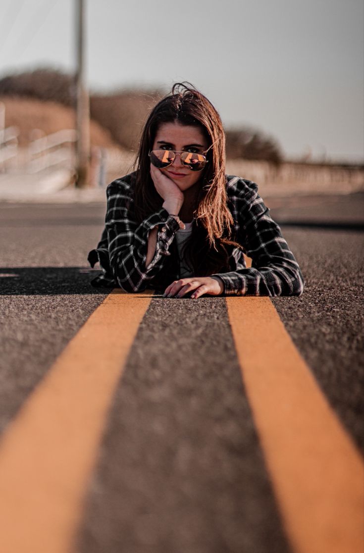 a woman laying on the ground with her hand under her chin and looking at the camera