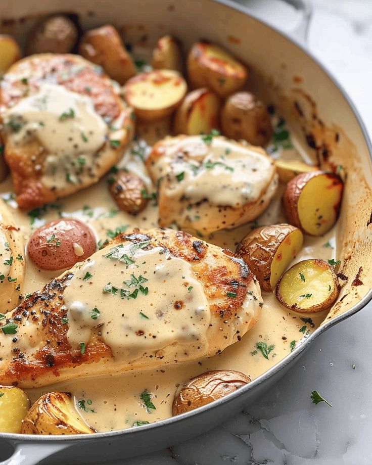 a pan filled with chicken, potatoes and gravy on top of a table