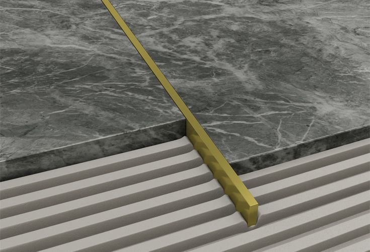 a yellow metal object sitting on top of a marble floor next to a white wall