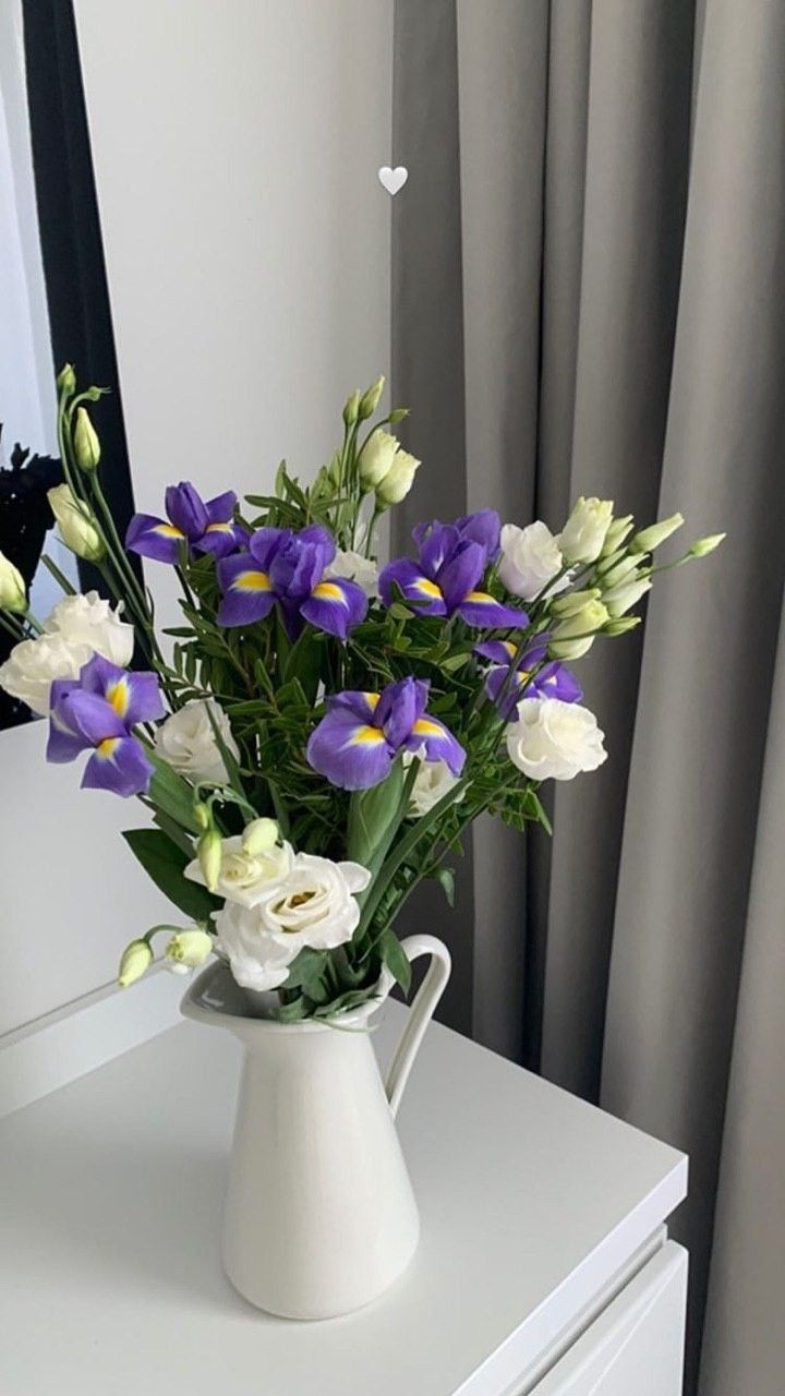 a white vase filled with purple and white flowers