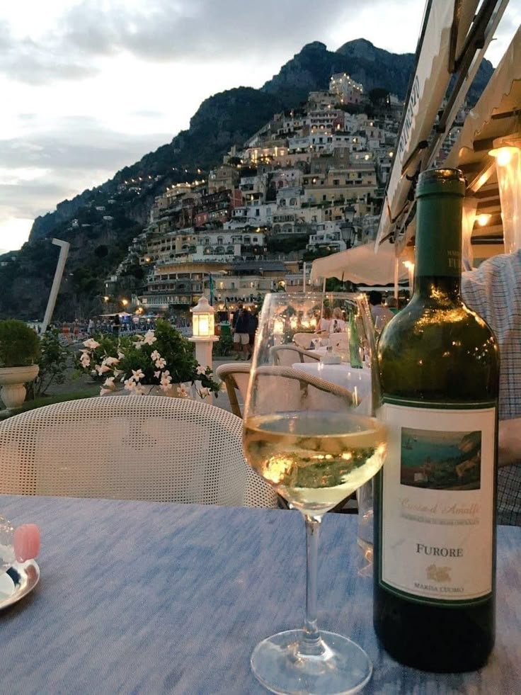 a bottle of wine sitting on top of a table next to a glass of wine