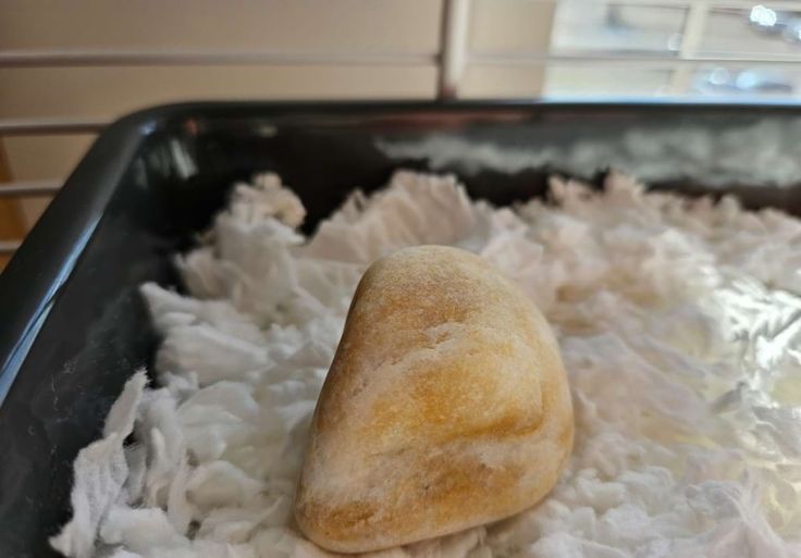 an uncooked loaf of bread sitting on top of shredded white paper in a pan