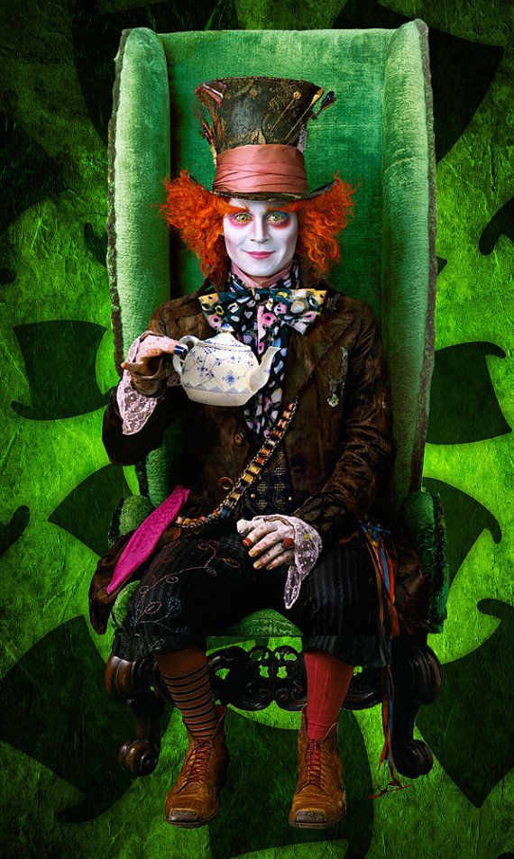 a creepy clown sitting in a green chair holding a tea cup and looking at the camera