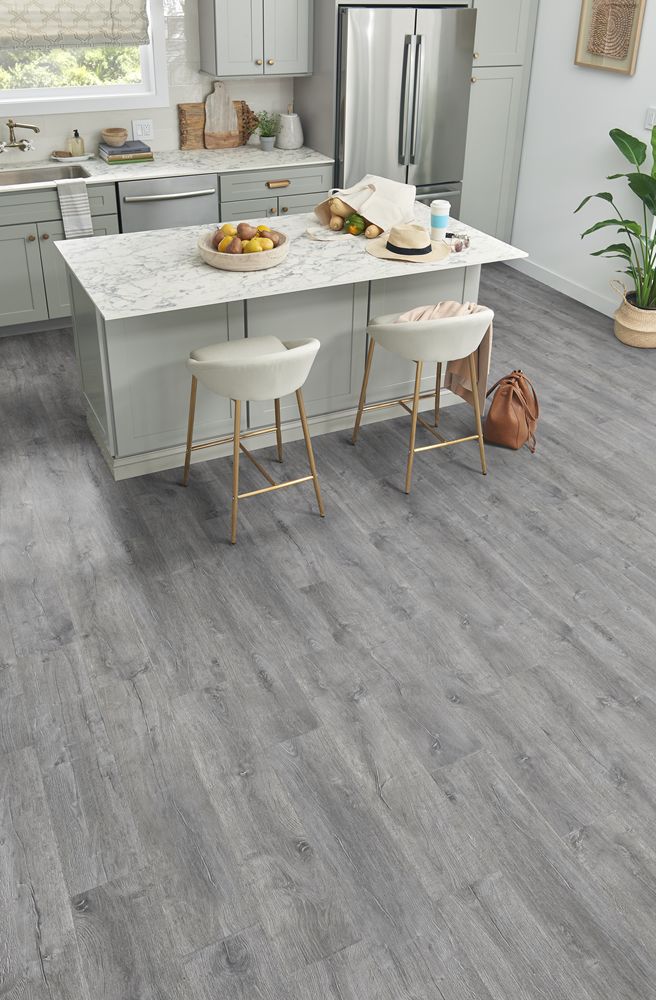 a kitchen with white cabinets and wood flooring is pictured in this image, there are two stools at the center of the island