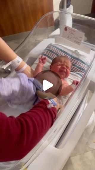 a baby in a hospital bed being held by an adult