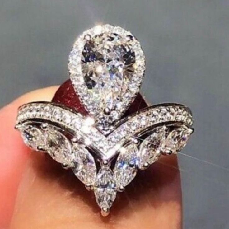 a close up of a person's hand holding a ring with diamonds on it