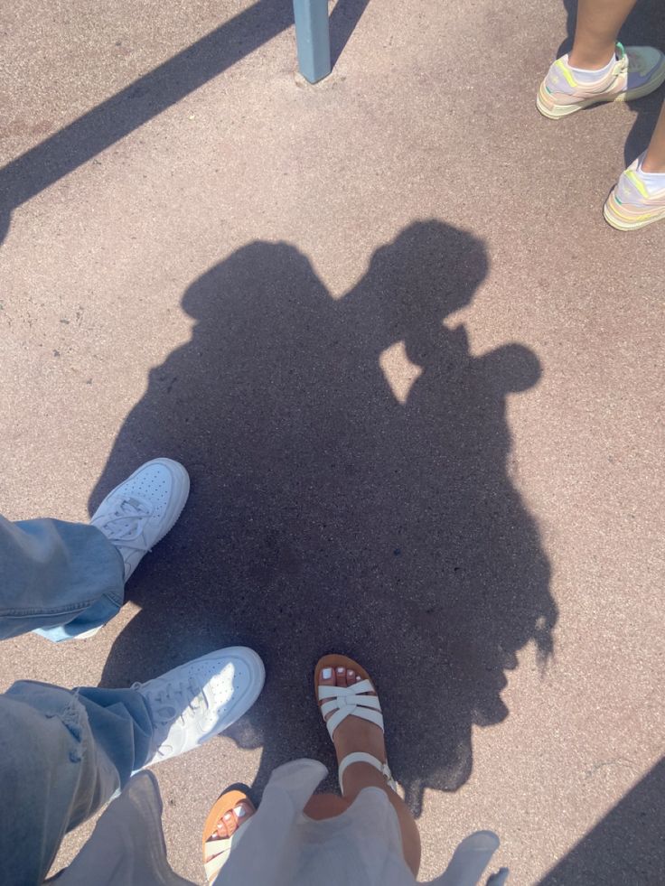 two people standing next to each other with their shadows on the ground and one person's shadow