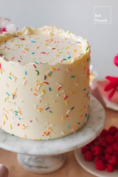 a cake with white frosting and sprinkles sitting on top of a table