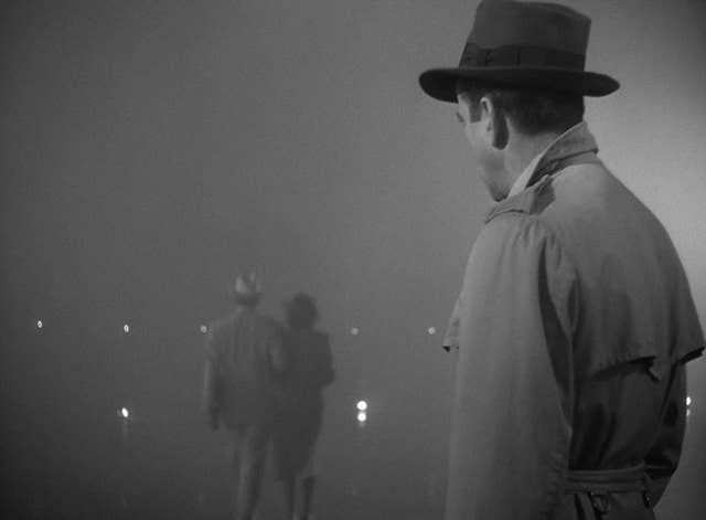 two men are standing in the fog with one man wearing a top hat and coat