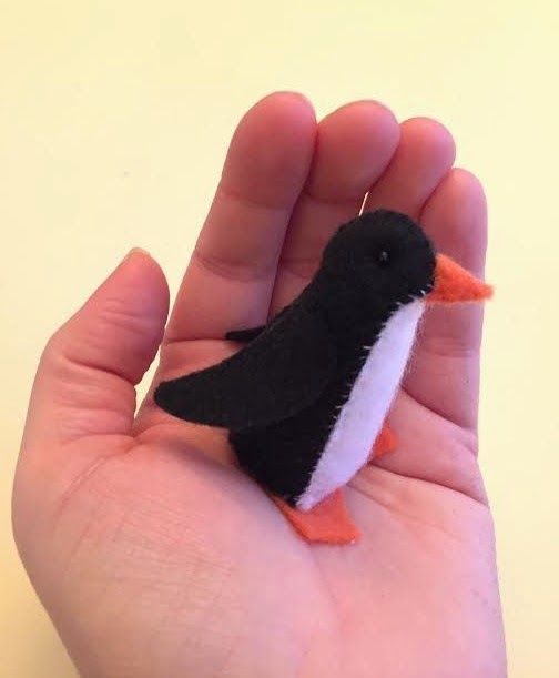 a small black and white penguin sitting on someone's hand