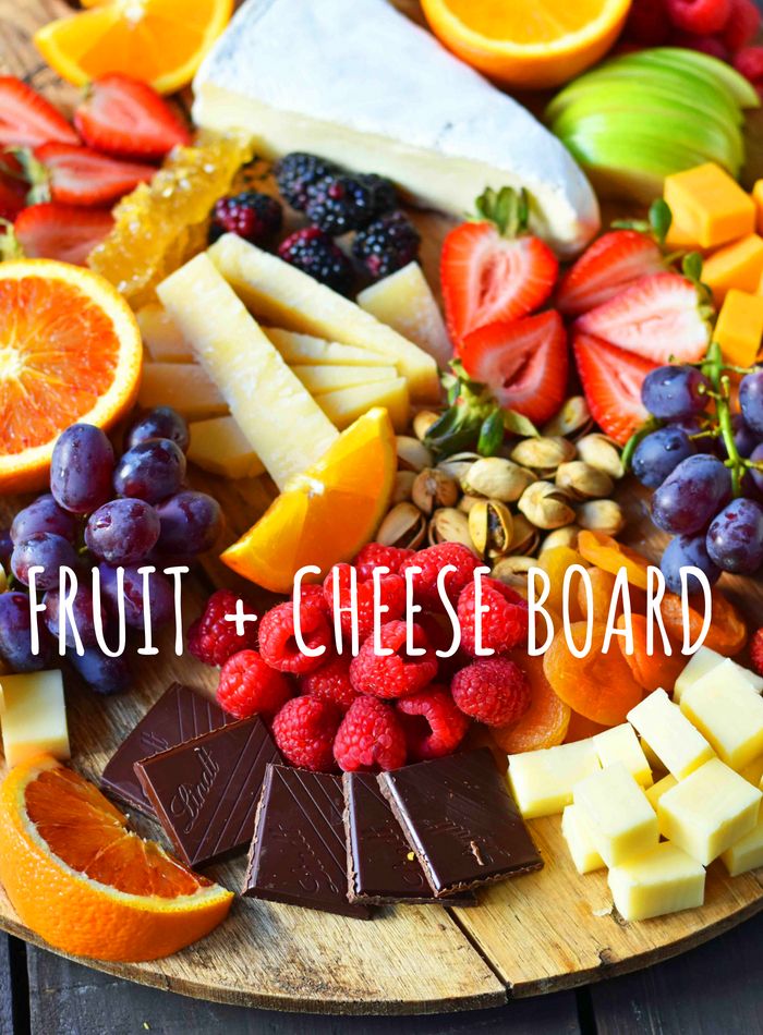 fruit and cheese board with oranges, raspberries, pineapples, grapes, walnuts