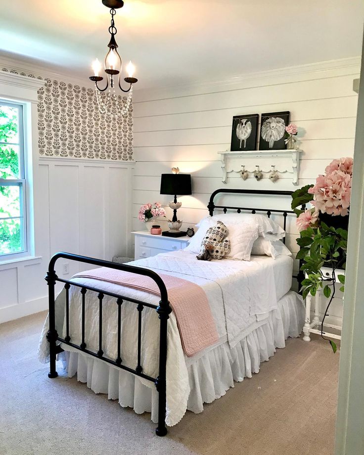 a bedroom with white walls and pink flowers on the nightstands in front of the bed