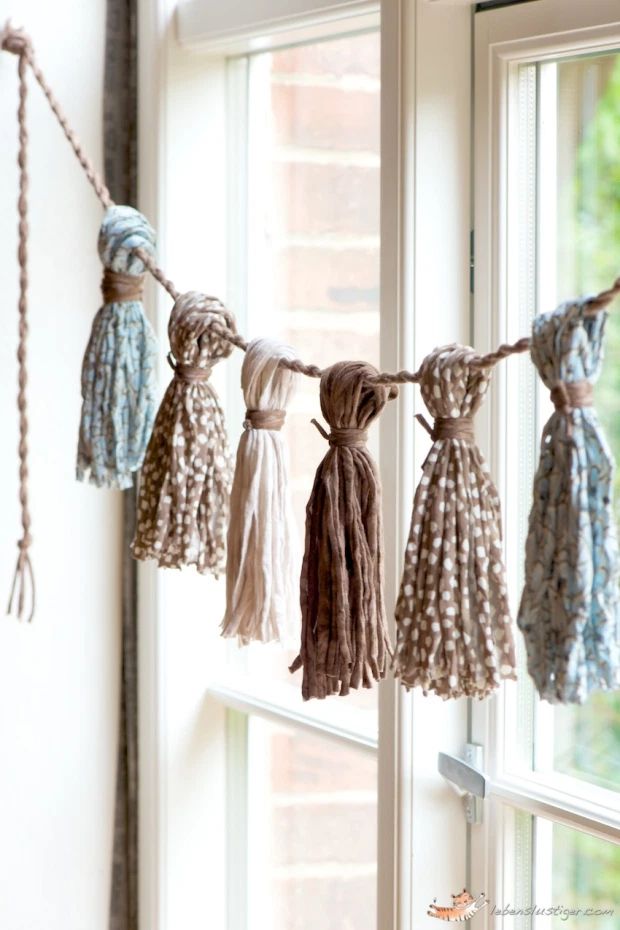 several tassels hanging from a clothes line in front of a window