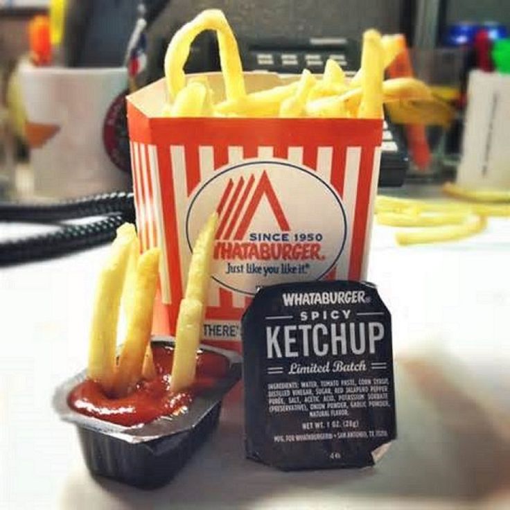 french fries and ketchup in a container on a table next to a sign