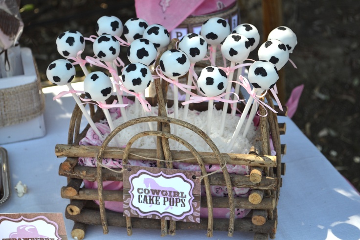 a table topped with marshmallows and cake pops covered in cow's milk