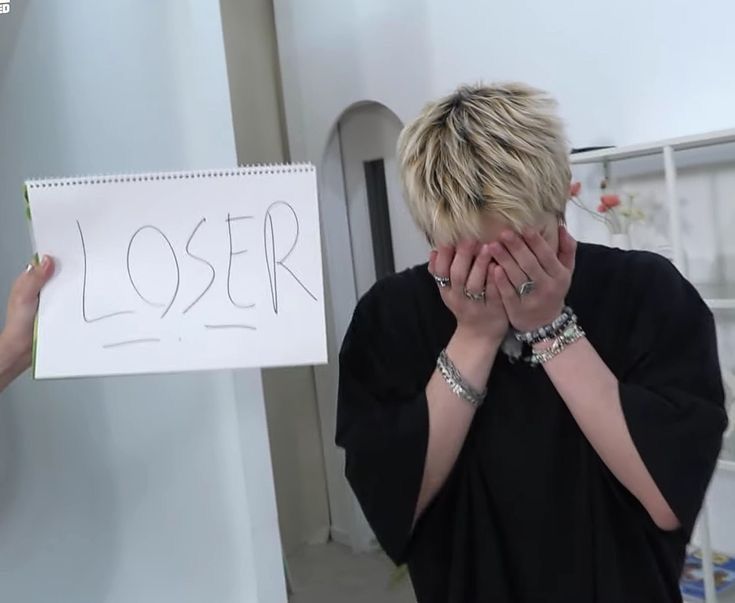 a woman covering her face next to a sign with the word closer written on it