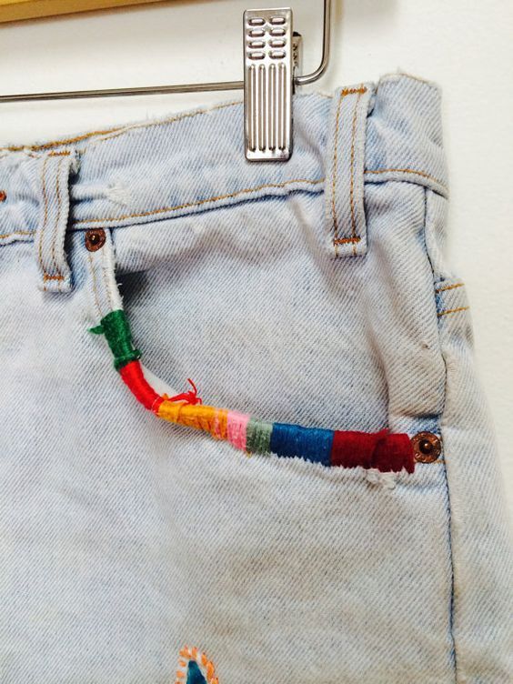 a pair of jeans with colorful beads hanging from the back pocket and a toothbrush sticking out of it