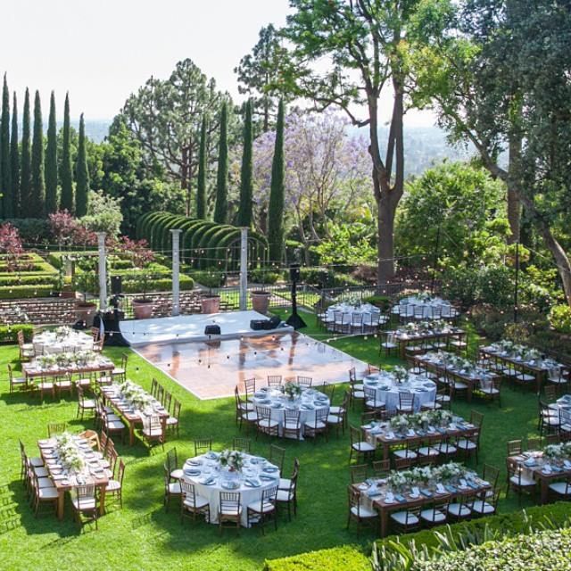 an outdoor dining area with tables and chairs set up in the grass, surrounded by trees