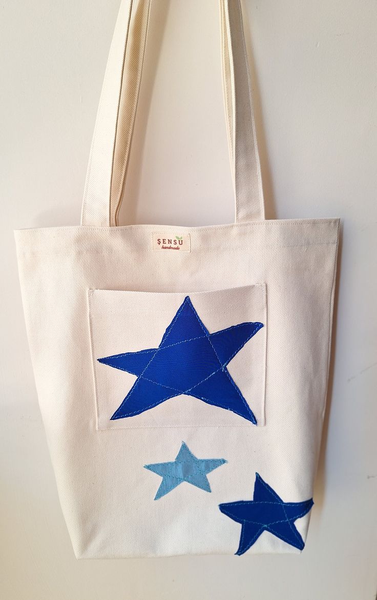 a white bag with blue stars hanging from it's front and side pockets, on a wall