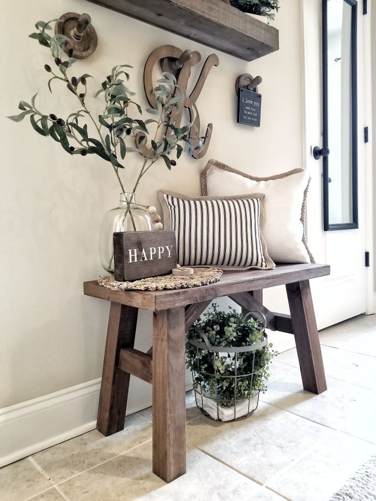 a wooden bench sitting in front of a wall with some plants on top of it