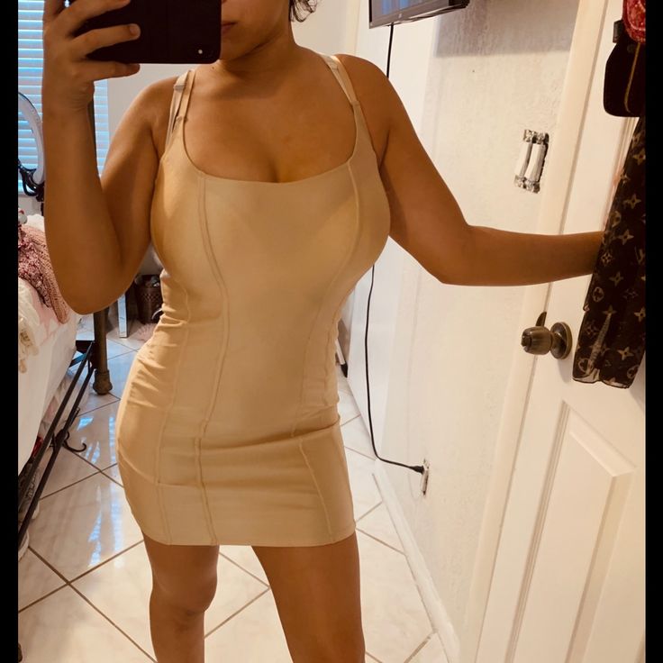 a woman taking a selfie in a tan dress