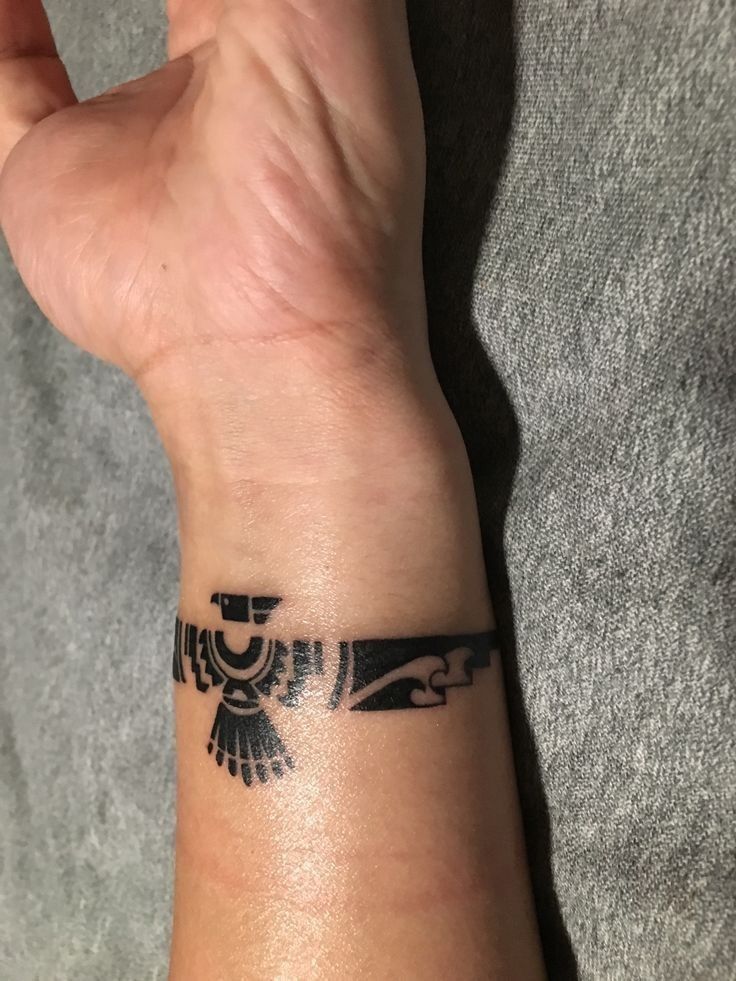 a person's arm with a tattoo on it that has an egyptian bird design