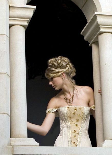 a woman in a white corset looking out from an open window with columns