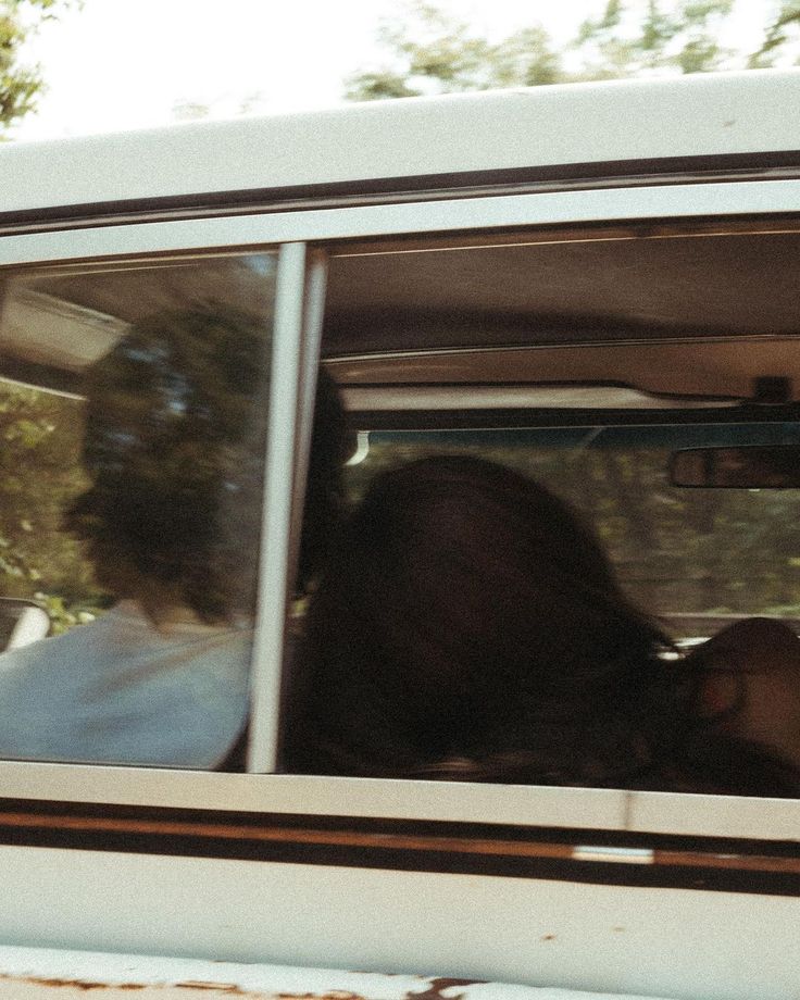 two people are sitting in the back seat of a car with their heads out the window