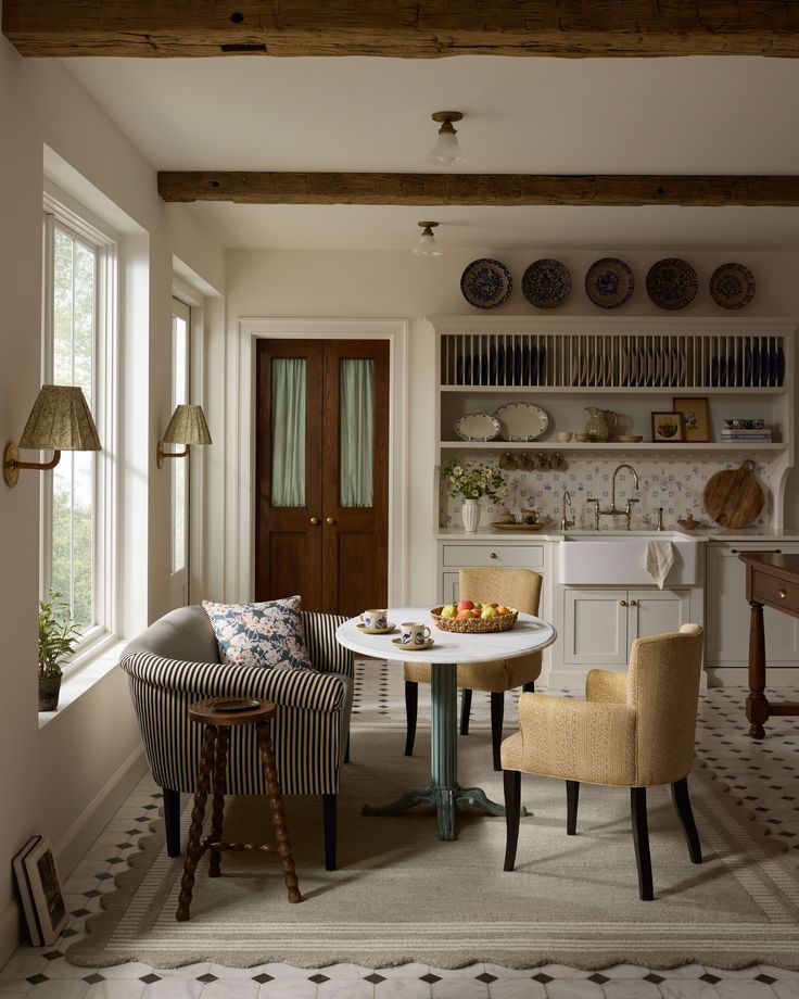 two chairs and a table in a room with white walls, wood beams and open shelving